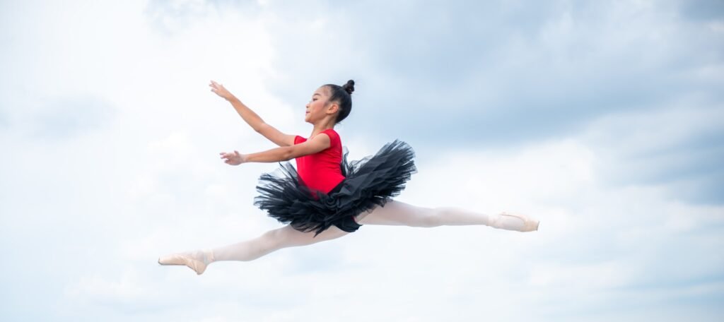 Beautiful young ballet dancer jumping on a color background.